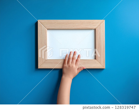 Toddler's hands holding a wooden frame 128319747