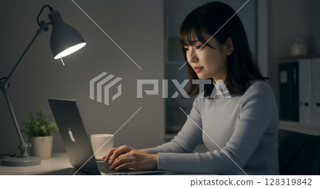 Business portrait of a young woman working on a computer at her desk at night 128319842