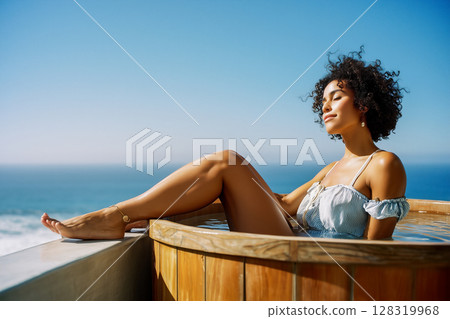 A woman is sitting in a hot tub with her legs crossed 128319968