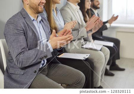 Smiling business professionals clapping hands, showing support and appreciation after training. 128320111