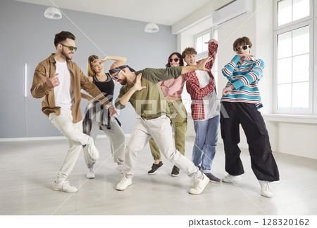 Group of trendy young people dancing in studio, performing hip hop moves and expressing energy. Group of trendy young people dancing in studio, performing hip hop moves and expressing energy. 128320162