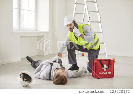 Construction worker beside unconscious coworker calling emergency services for medical help. Construction worker beside unconscious coworker calling emergency services for medical help. 128320172