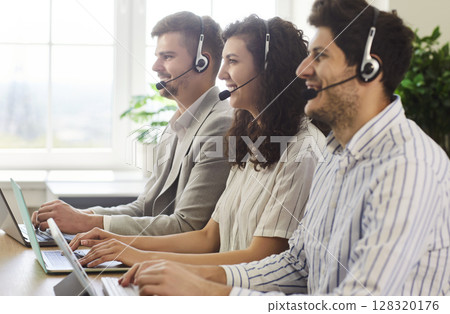 Smiling young call center operators in headsets providing customer support service in office. Smiling young call center operators in headsets providing customer support service in office. 128320176