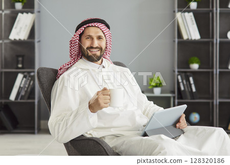 Arabian man having coffee break during doing remote work posing with cup of coffee, digital tablet Arabian man having coffee break during doing remote work posing with cup of coffee, digital tablet 128320186