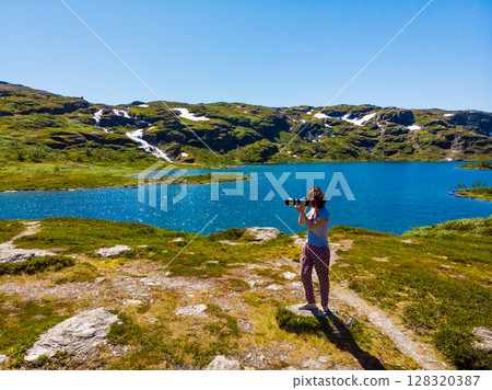 Tourist taking photo in norwegian nature Tourist taking photo in norwegian nature 128320387