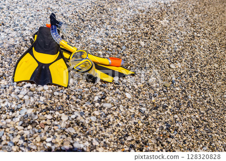 Flippers and snorkeling tube on sea shore 128320828
