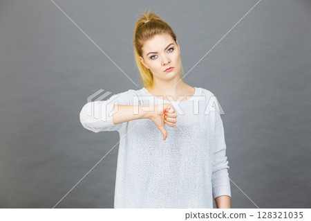 Sad woman showing thumb down gesture Sad woman showing thumb down gesture 128321035