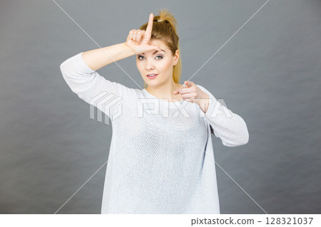 Woman showing loser gesture with L on forehead 128321037