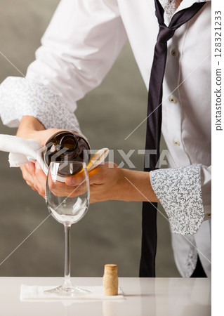 Man waiter pouring wine into glass. 128321233