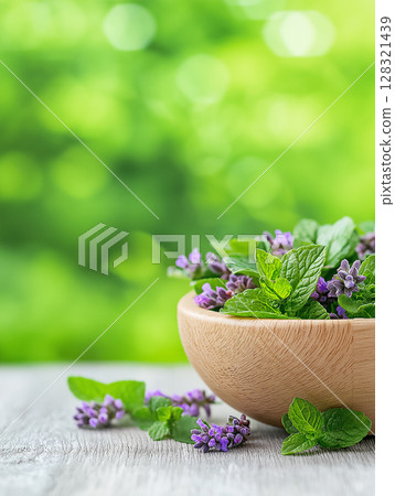 Fresh herbs including mint and lavender in a wooden bowl on a sunny nature background Fresh herbs including mint and lavender in a wooden bowl on a sunny nature background 128321439