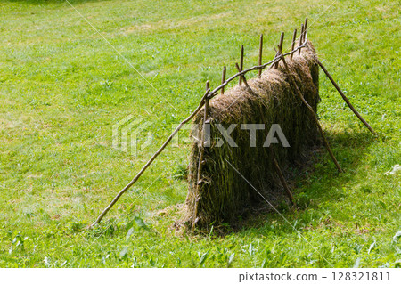 Drying grass hay straws on wooden fence 128321811