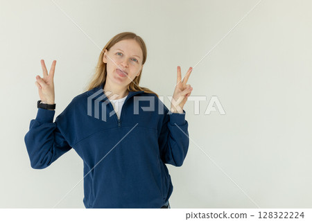 Photo of young attractive girl happy positive smile show peace cool v-sign isolated over white background Photo of young attractive girl happy positive smile show peace cool v-sign isolated over white background 128322224