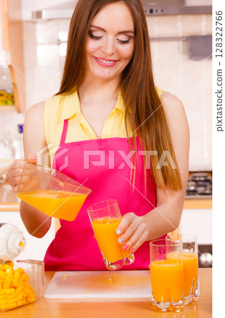 Woman make orange juice in juicer machine pouring drink in glass 128322766