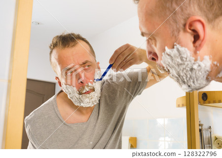 Guy shaving his beard in bathroom Guy shaving his beard in bathroom 128322796