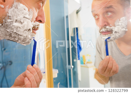 Guy shaving his beard in bathroom 128322799