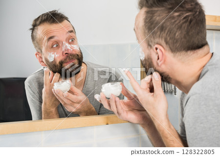 Man applying moisturizer cream in bathroom Man applying moisturizer cream in bathroom 128322805