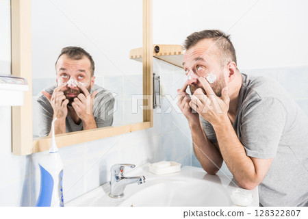 Man applying moisturizer cream in bathroom 128322807