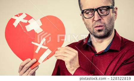 Thinking adult man holding broken heart Thinking adult man holding broken heart 128322819