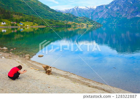 Tourist taking photo at norwegian fjord Tourist taking photo at norwegian fjord 128322887