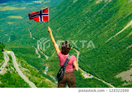 Tourist with norwegian flag on Trollstigen viewpoint Tourist with norwegian flag on Trollstigen viewpoint 128322890
