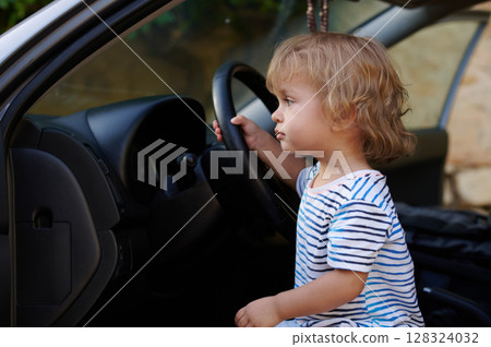 Adorable Child Pretending to Drive a Car Steering Wheel While Sitting Inside 128324032