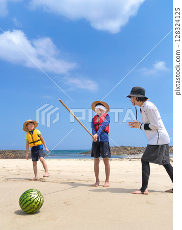Family leisure scene enjoying watermelon splitting at the beach in summer 128324125