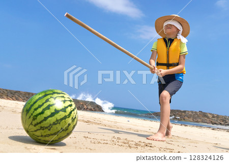 A boy enjoying splitting a watermelon on the beach in summer 128324126