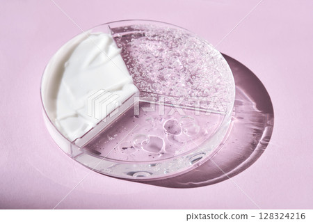 A three-section petri dish with textures of cream, cosmetic oil and serum. Purple background. 128324216