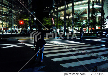 Tokyo International Forum at night, security guards, guides, and guards standing at a crosswalk 128324459
