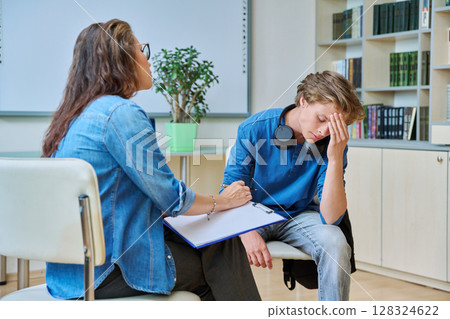 Sad teenage boy in mental therapy session, talking with school counsellor Sad teenage boy in mental therapy session, talking with school counsellor 128324622