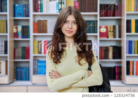 Portrait of teenage beautiful girl high school student posing in library classroom 128324736
