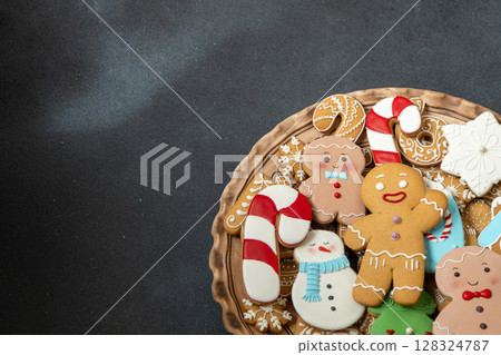 Gingerbread cookies with icing decoration. Christmas food. Gingerbread man baking. Top view table. Xmas sweet on black background copy space 128324787