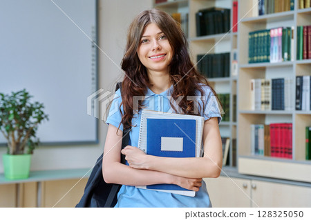 Portrait of teenage beautiful girl high school student posing in library classroom 128325050