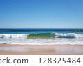 Crystal clear ocean waves under a bright blue sky and sunlight 128325484
