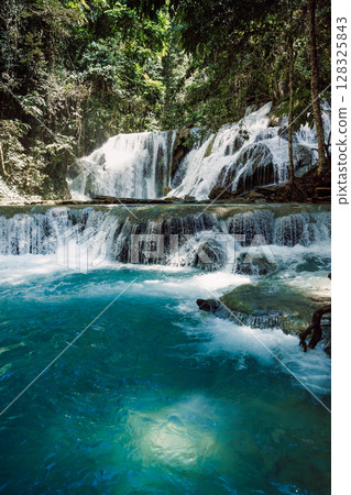 Cascade waterfall with blue water in tropical rain forest 128325843