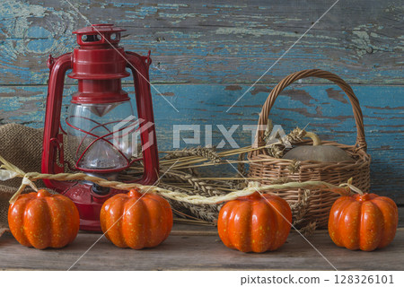 Thanksgiving or autumn still life: vintage lantern, pumkin decorations, wicker basket and cereal on a old wooden background Thanksgiving or autumn still life: vintage lantern, pumkin decorations, wicker basket and cereal on a old wooden background 128326101