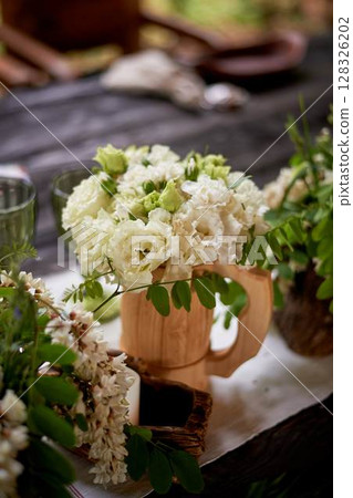 Banquet decoration in a simple rustic style with grass, greenery, simple objects and fabrics. Wedding table setting for guests Banquet decoration in a simple rustic style with grass, greenery, simple objects and fabrics. Wedding table setting for guests 128326202