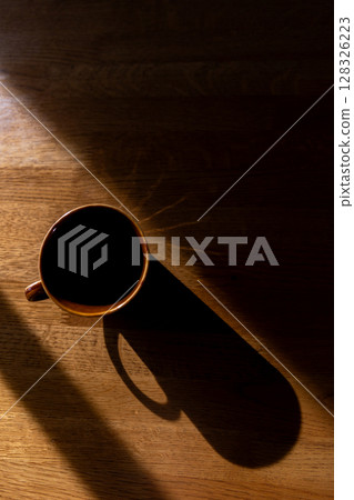 A cup on a table and a long shadow 128326223