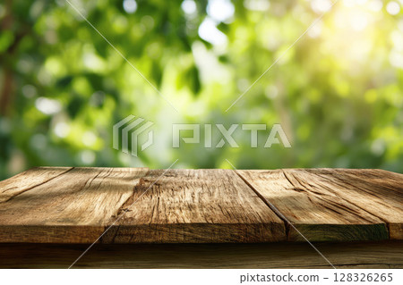 Rustic wooden table surface with blurred foliage and sunlight in background 128326265