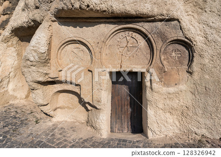 St. Catherine's Chapel rock-cut facade, featuring carved religious symbols and wooden door, Cappadocia, Turkey St. Catherine's Chapel rock-cut facade, featuring carved religious symbols and wooden door, Cappadocia, Turkey 128326942