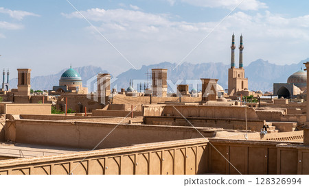 Yazd cityscape featuring traditional mudbrick buildings, iconic windcatcher towers, and Iranian architecture Yazd cityscape featuring traditional mudbrick buildings, iconic windcatcher towers, and Iranian architecture 128326994