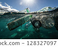 Plastic bottles and glasses drift in the ocean, illuminated by sunlight, highlighting the human impact on marine environments and sustainability. 128327097