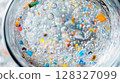 Detailed examination reveals colorful microplastic particles floating in clear water, highlighting environmental pollution concerns. 128327099