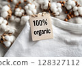 Soft organic cotton t-shirt features a 100% organic tag, surrounded by cotton and wooden beads, representing sustainable fashion choices. 128327112