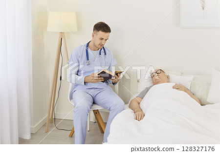 In bright hospital room, compassionate doctor reads book while sitting next to his elderly patient. In bright hospital room, compassionate doctor reads book while sitting next to his elderly patient. 128327176