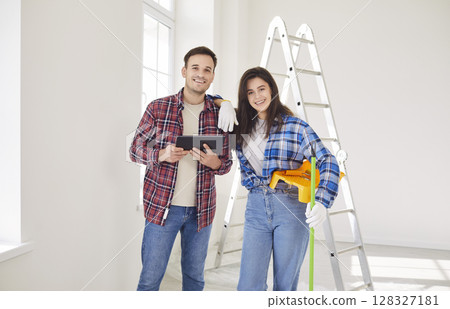 Happy couple after moving, planning future repair, using tablet in new home, young working friends 128327181