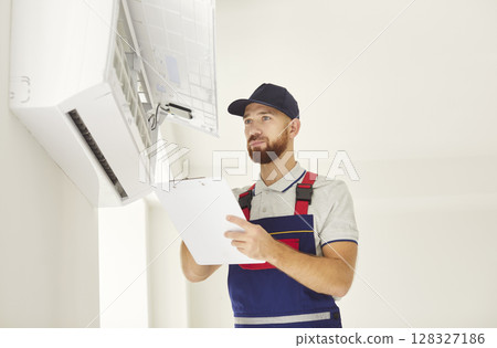 Young professional electrician man or technician maintaining air conditioner in new apartment. Young professional electrician man or technician maintaining air conditioner in new apartment. 128327186