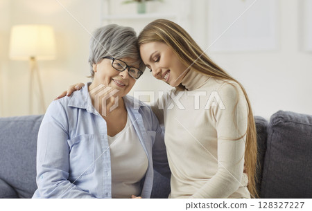 Happy adult woman embracing her senior grey haired mother Happy adult woman embracing her senior grey haired mother 128327227
