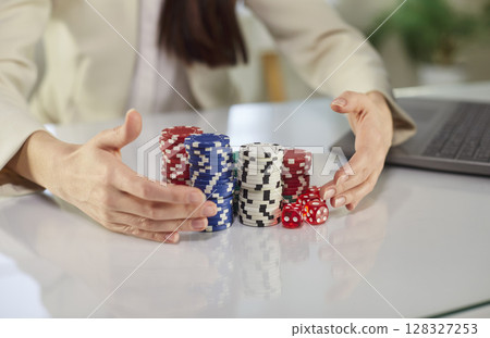 Closeup of woman hands holding poker chips sitting at desk and playing gambling at home Closeup of woman hands holding poker chips sitting at desk and playing gambling at home 128327253