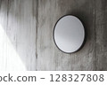 Modern Round Mirror Mounted on a Textured Concrete Wall with Natural Light Reflection 128327808